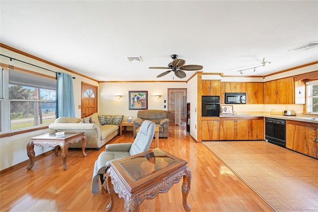 living room with a healthy amount of sunlight, crown molding, and light hardwood / wood-style floors