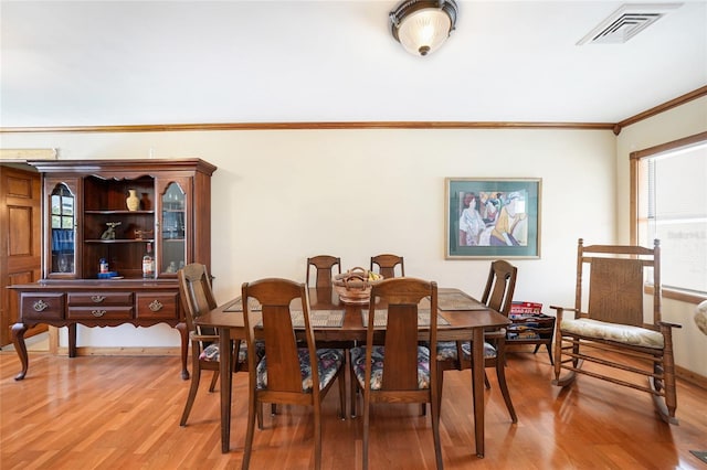 dining area with light hardwood / wood-style flooring and ornamental molding