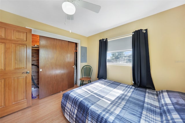 bedroom featuring electric panel, ceiling fan, a closet, and light wood-type flooring