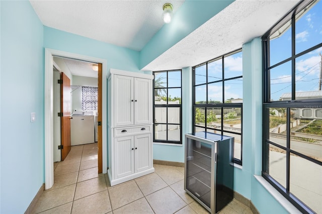 hall featuring washer / clothes dryer, light tile patterned floors, and a textured ceiling