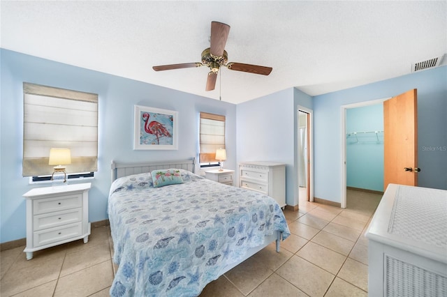 tiled bedroom with ceiling fan, a closet, a spacious closet, and a textured ceiling