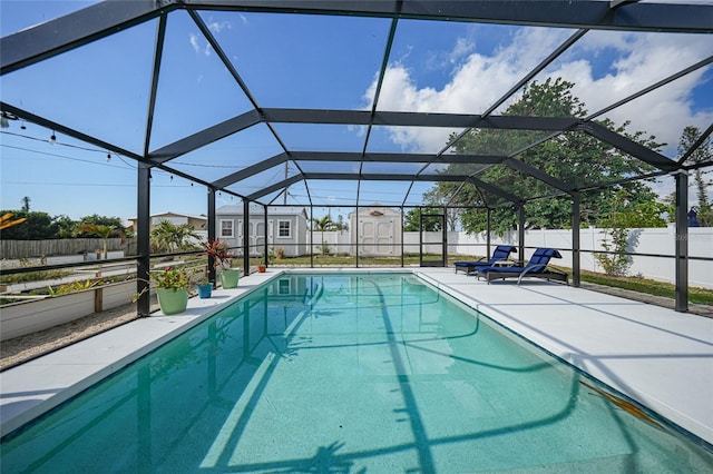 view of swimming pool with glass enclosure and a shed