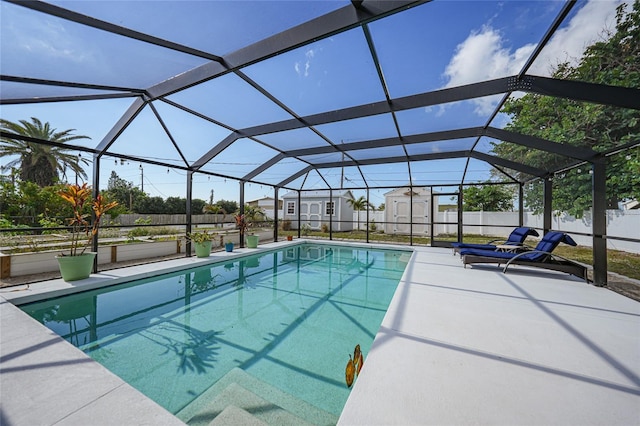 view of swimming pool with a storage unit, a patio area, and a lanai