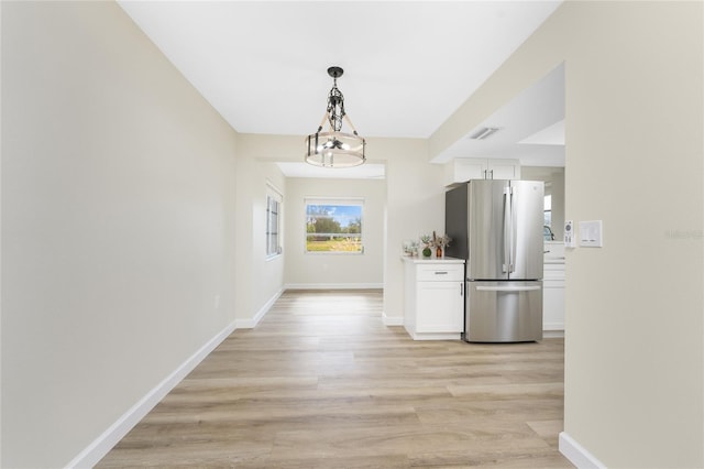 hallway with an inviting chandelier and light hardwood / wood-style flooring