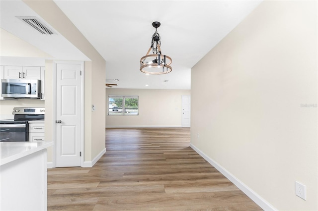 hallway with light hardwood / wood-style flooring and an inviting chandelier