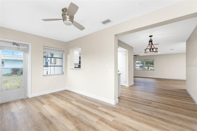 spare room featuring ceiling fan with notable chandelier and light hardwood / wood-style floors