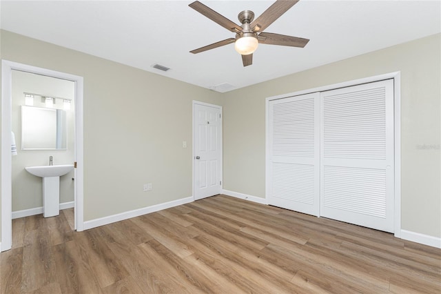 unfurnished bedroom featuring ceiling fan, light hardwood / wood-style floors, connected bathroom, and a closet