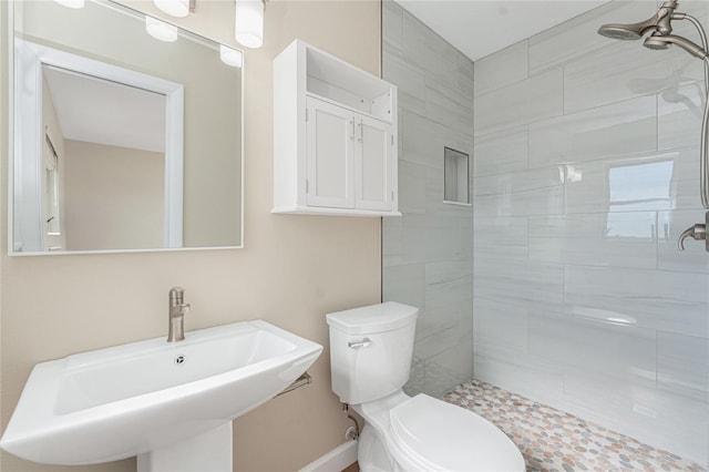 bathroom with toilet, sink, and a tile shower