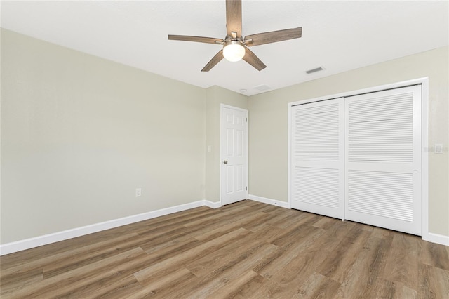 unfurnished bedroom featuring hardwood / wood-style floors, a closet, and ceiling fan