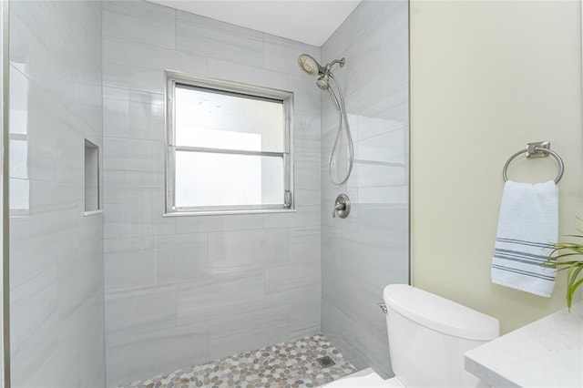 bathroom featuring tiled shower and toilet