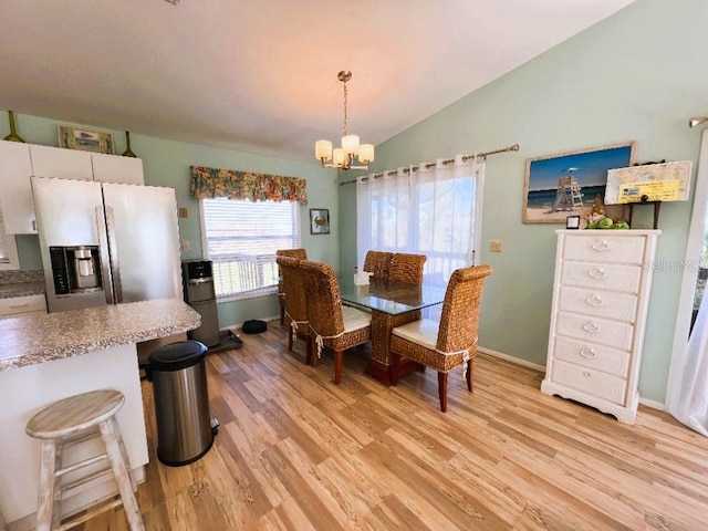 dining space featuring light wood finished floors, baseboards, vaulted ceiling, and a notable chandelier