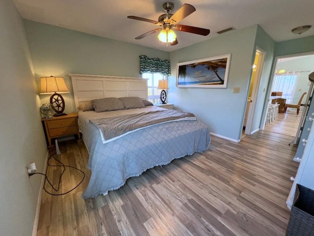 bedroom with baseboards, visible vents, ceiling fan, and wood finished floors