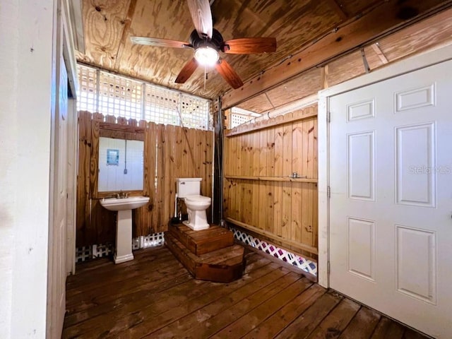 bathroom with wood-type flooring, sink, toilet, and wood walls