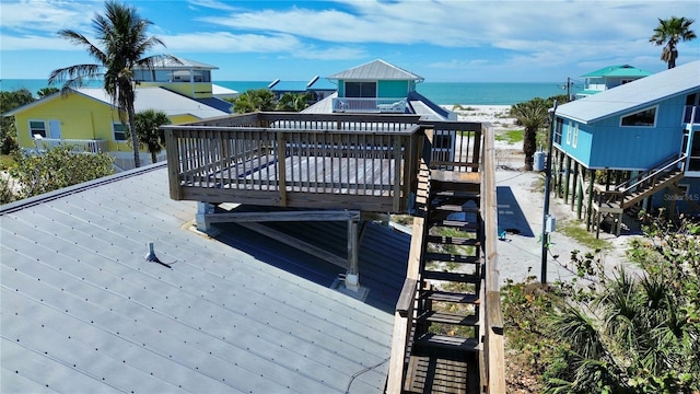 exterior space featuring stairs, a deck with water view, and a view of the beach