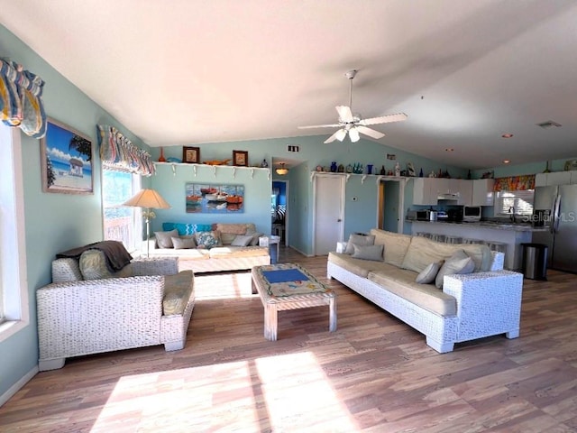 living room with ceiling fan, visible vents, vaulted ceiling, and wood finished floors