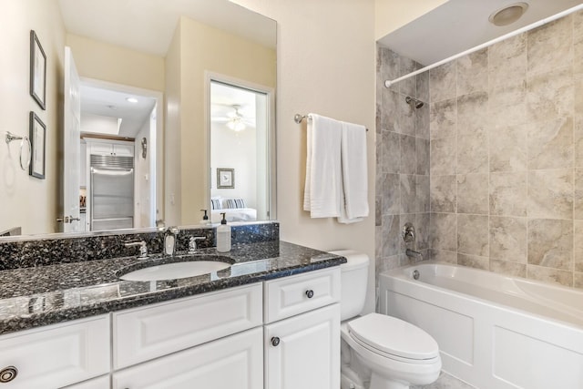 full bathroom with vanity, toilet, tiled shower / bath, and ceiling fan