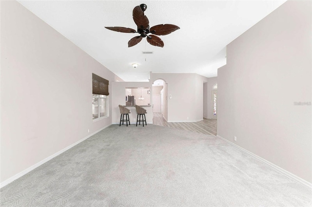 unfurnished living room featuring light carpet, ceiling fan, and a wealth of natural light