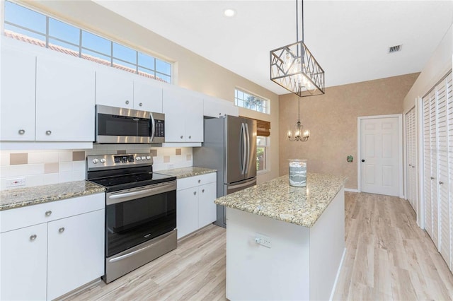 kitchen featuring a chandelier, a kitchen island, decorative light fixtures, stainless steel appliances, and white cabinets