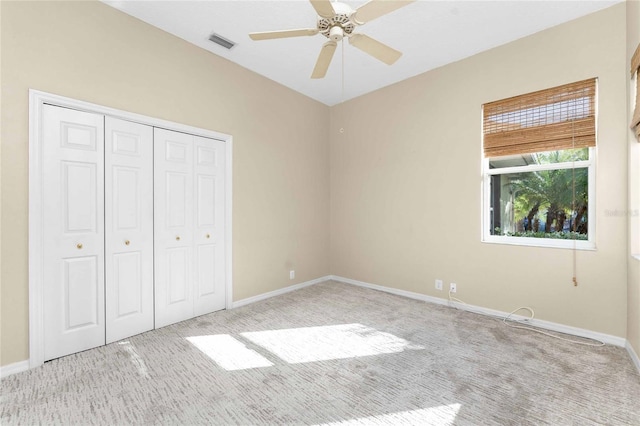 unfurnished bedroom featuring a closet, light colored carpet, and ceiling fan