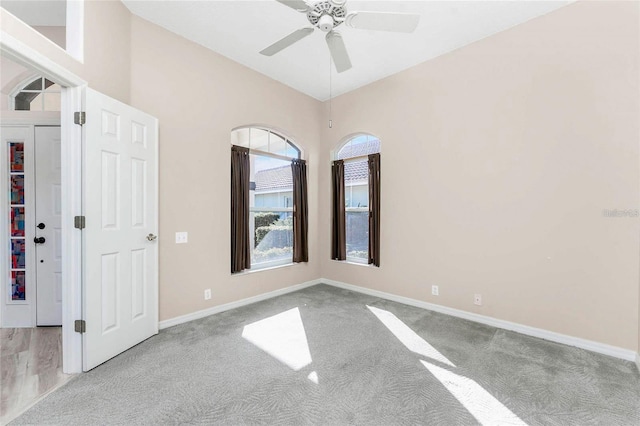 empty room with ceiling fan, vaulted ceiling, and light colored carpet