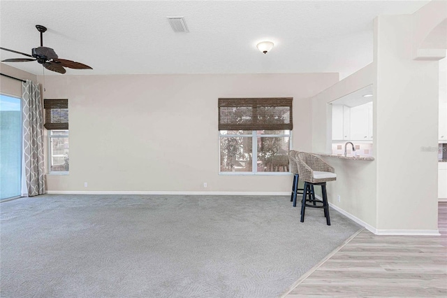 spare room with light carpet, plenty of natural light, ceiling fan, and a textured ceiling