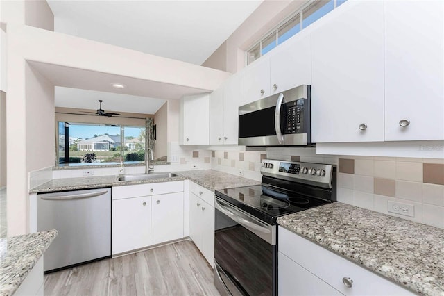 kitchen with appliances with stainless steel finishes, sink, light stone counters, and white cabinets