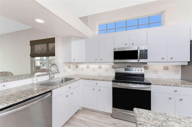 kitchen featuring white cabinetry, stainless steel appliances, backsplash, and sink