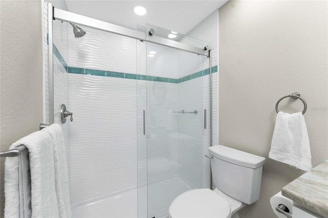 bathroom featuring a shower with door and toilet