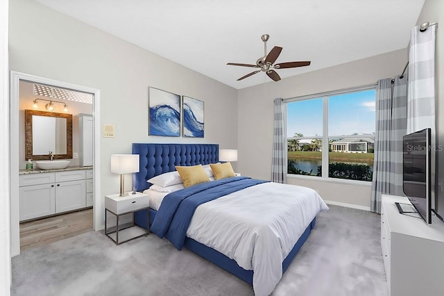 carpeted bedroom featuring ensuite bathroom, ceiling fan, and sink