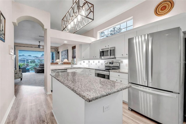 kitchen featuring white cabinetry, stainless steel appliances, hanging light fixtures, a kitchen island, and decorative backsplash