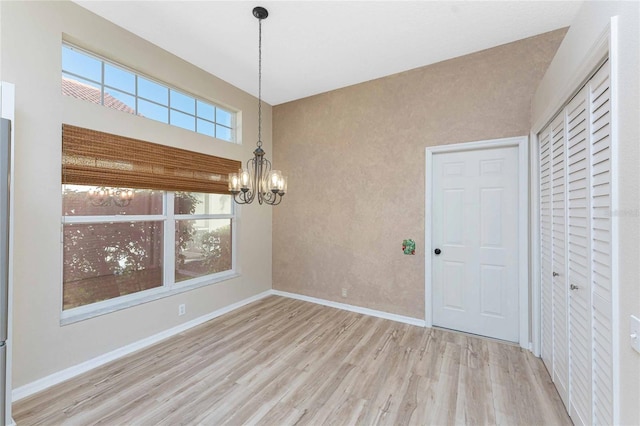 unfurnished dining area featuring light hardwood / wood-style floors and a chandelier