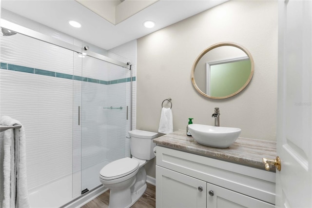 bathroom with toilet, vanity, an enclosed shower, and wood-type flooring