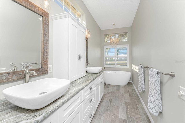 bathroom with hardwood / wood-style flooring, a washtub, a textured ceiling, vanity, and a chandelier