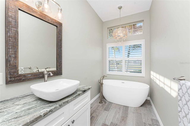 bathroom featuring hardwood / wood-style floors, a notable chandelier, a tub to relax in, and vanity