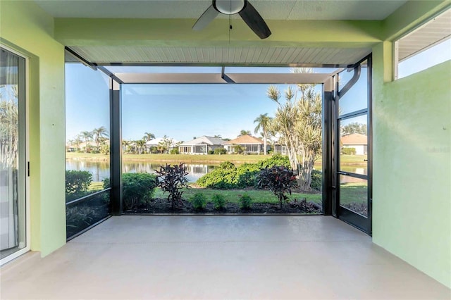 unfurnished sunroom featuring ceiling fan and a water view