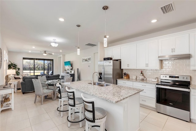 kitchen with stainless steel appliances, ceiling fan, sink, white cabinets, and an island with sink