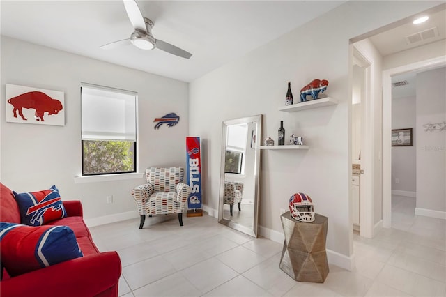 living area with light tile patterned floors and ceiling fan