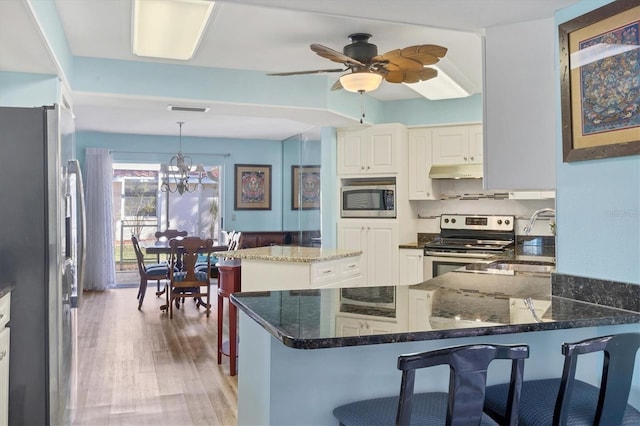 kitchen with kitchen peninsula, decorative light fixtures, stainless steel appliances, and sink