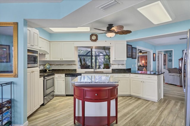 kitchen featuring white cabinets, light hardwood / wood-style floors, a kitchen bar, and appliances with stainless steel finishes