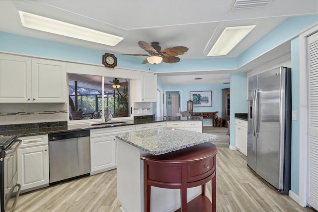 kitchen with dark stone counters, white cabinets, sink, appliances with stainless steel finishes, and kitchen peninsula