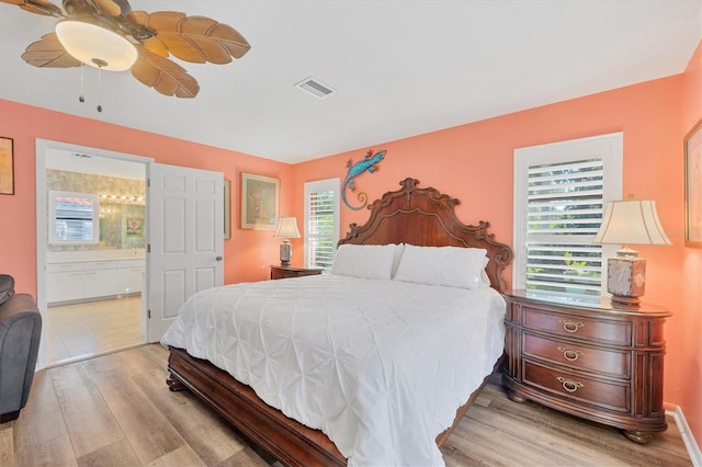 bedroom featuring ceiling fan, light hardwood / wood-style flooring, and ensuite bath