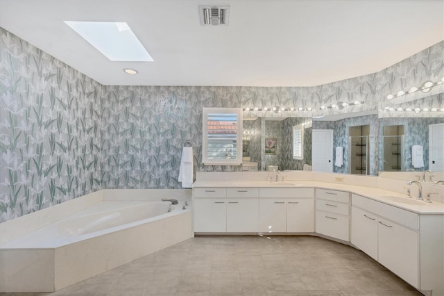 bathroom with shower with separate bathtub, vanity, a skylight, and tile patterned floors