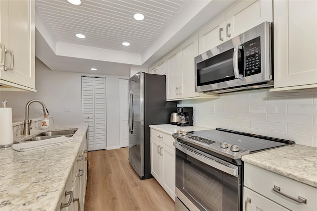 kitchen with sink, white cabinets, stainless steel appliances, and light wood-type flooring