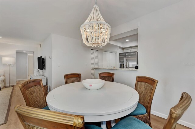 dining area with light hardwood / wood-style floors and an inviting chandelier