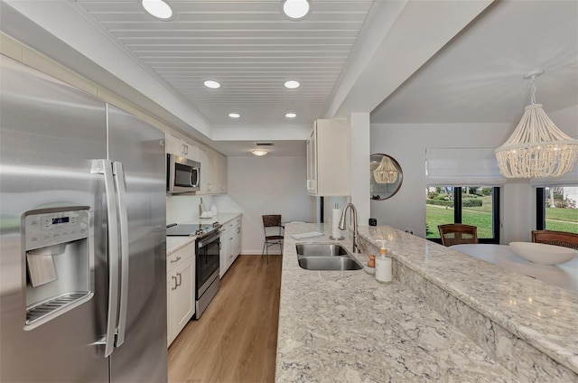 kitchen featuring pendant lighting, white cabinets, sink, light hardwood / wood-style flooring, and appliances with stainless steel finishes