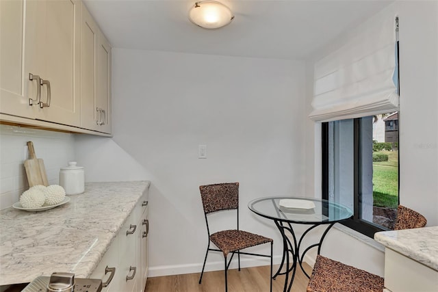 kitchen featuring a healthy amount of sunlight, light stone counters, light hardwood / wood-style floors, and tasteful backsplash