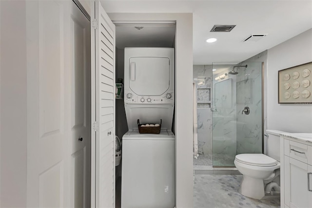 bathroom with an enclosed shower, vanity, toilet, and stacked washer / dryer