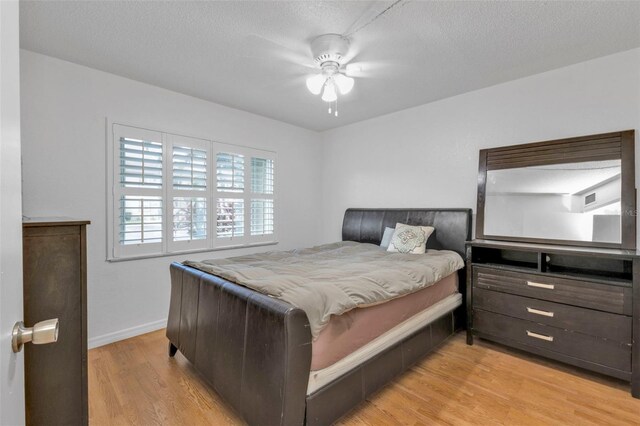 bedroom featuring ceiling fan, a textured ceiling, and light wood-type flooring