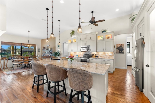 kitchen with pendant lighting, a large island with sink, white cabinets, a kitchen breakfast bar, and stainless steel appliances