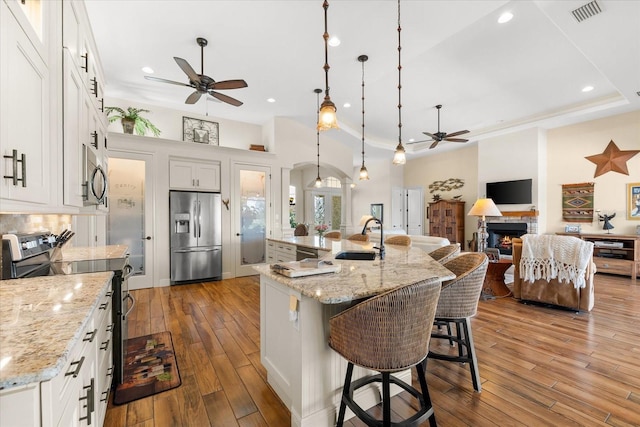 kitchen with sink, pendant lighting, a spacious island, white cabinets, and appliances with stainless steel finishes